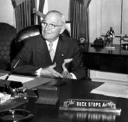 Photo of President Truman with the sign on his desk saying 'the buck stops here'